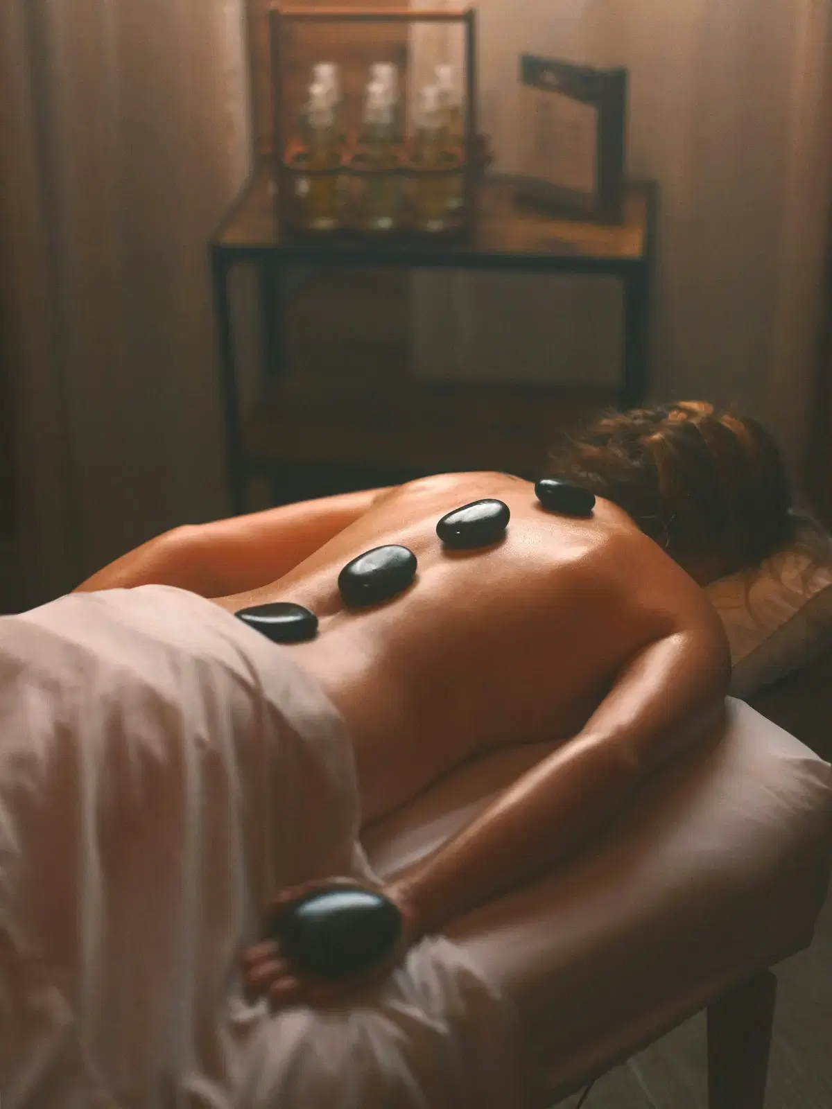 A woman lying face down with warm stones along her back