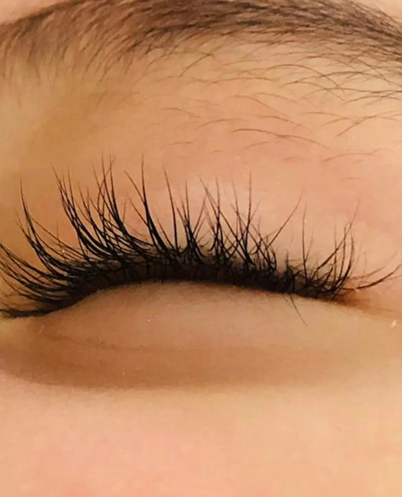 Close-up of a closed eye with softly curled natural lashes