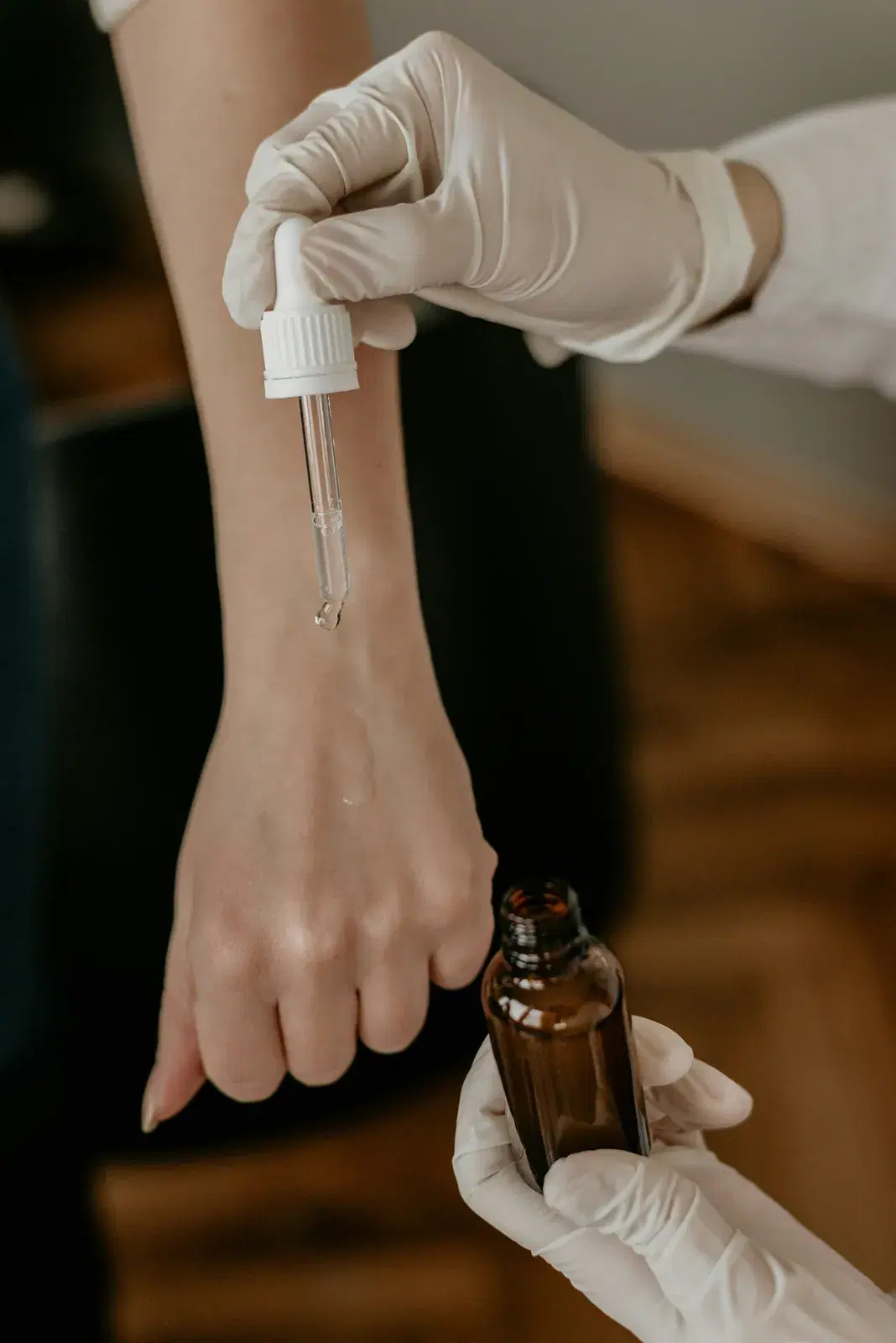 Gloved hands dropping serum onto a person’s forearm